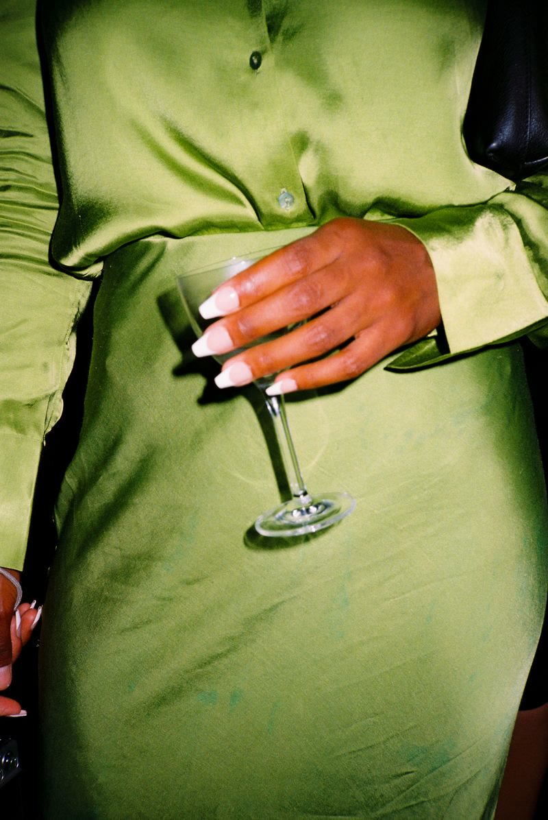 A coupe glass held against a green satin dress