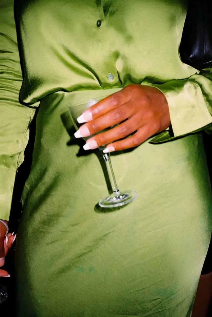 A coupe glass held against a green satin dress