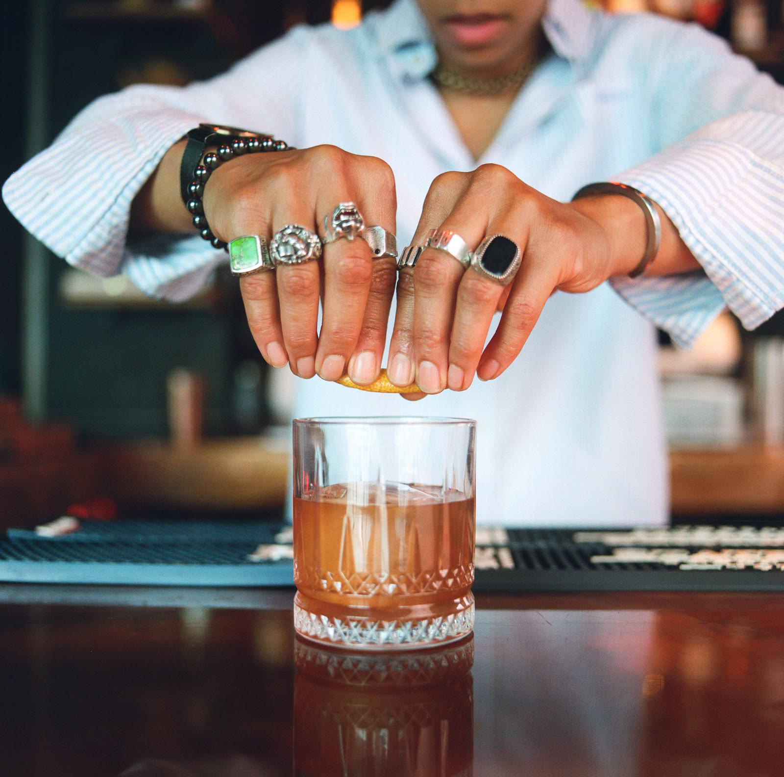 Hands squeezing citrus over a rocks glass at the bar